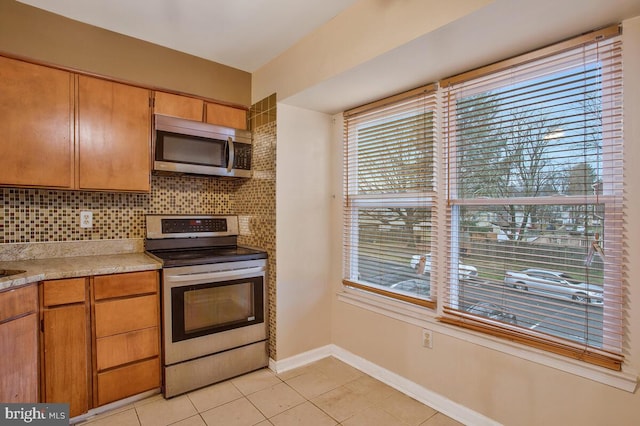 kitchen featuring light tile patterned flooring, stainless steel appliances, a wealth of natural light, and tasteful backsplash