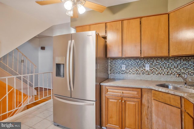 kitchen featuring ceiling fan, sink, stainless steel refrigerator with ice dispenser, decorative backsplash, and light tile patterned floors