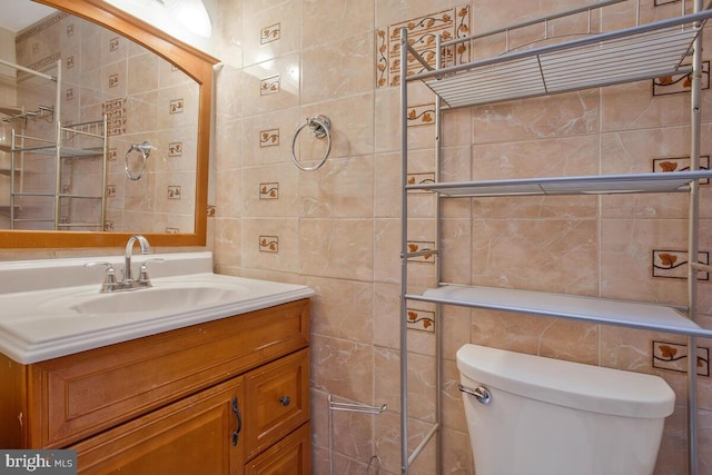 bathroom with vanity, toilet, and tile walls