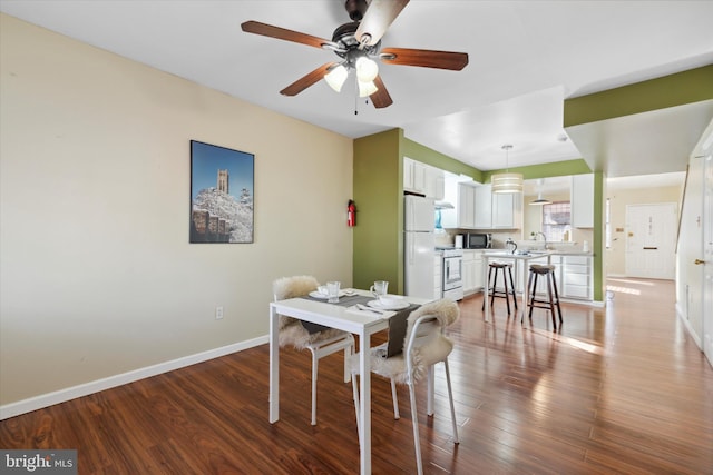 dining space featuring sink, wood-type flooring, and ceiling fan