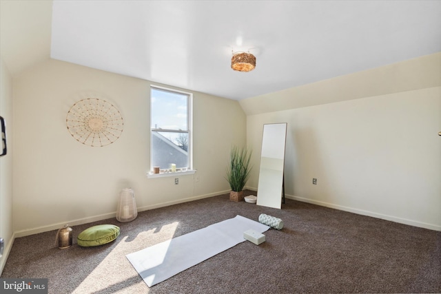 exercise room with vaulted ceiling and dark colored carpet