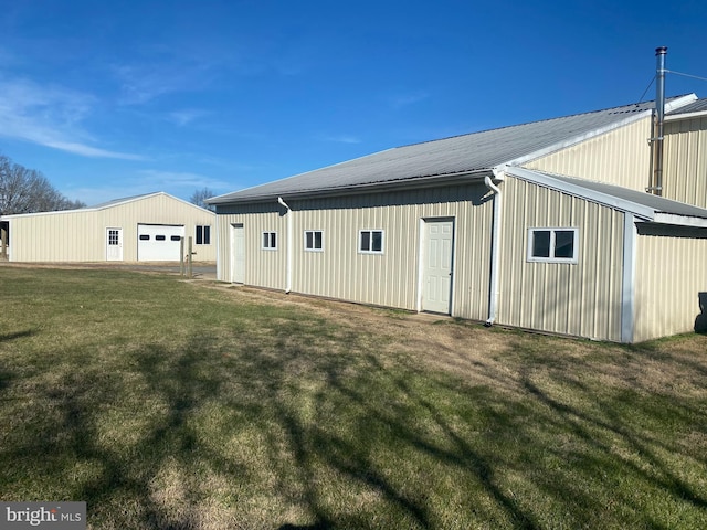 back of house featuring an outbuilding, a garage, and a lawn