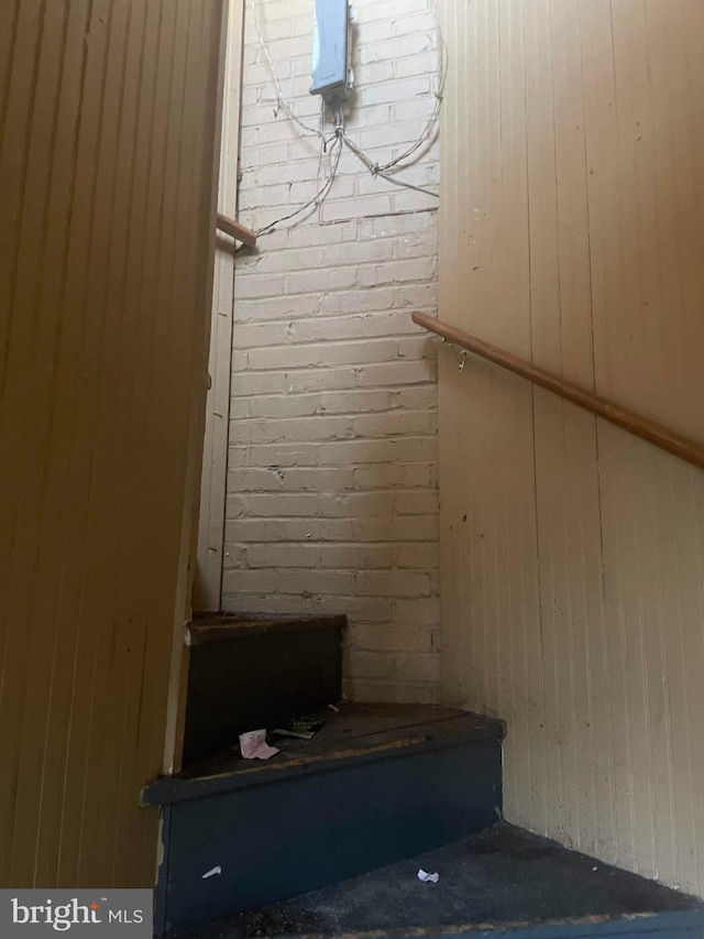 staircase with brick wall and wooden walls