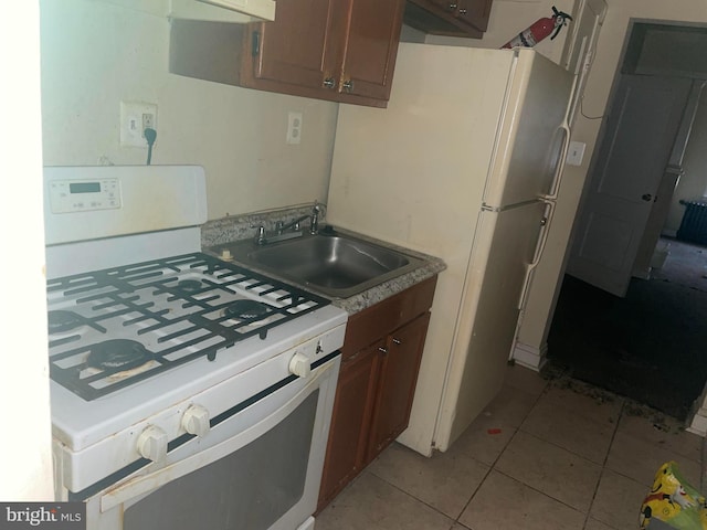 kitchen with light tile patterned flooring, white gas stove, and sink