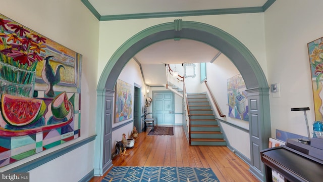 hallway with light wood-type flooring and ornamental molding