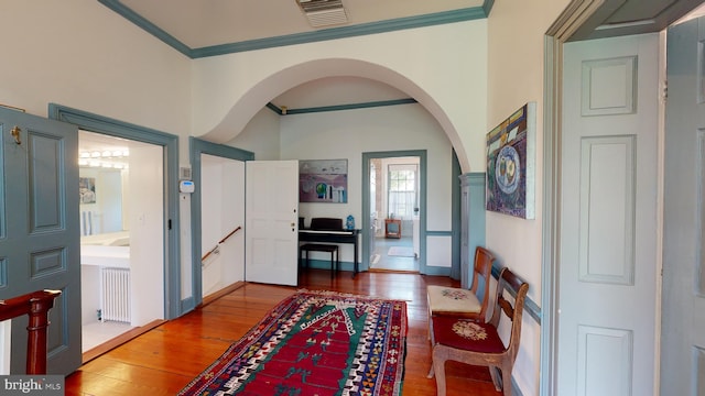 entrance foyer with hardwood / wood-style floors, radiator heating unit, and ornamental molding