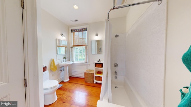 full bathroom with hardwood / wood-style flooring, toilet, shower / bathtub combination with curtain, and sink