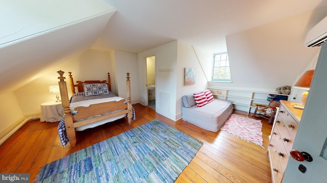 bedroom featuring a wall mounted air conditioner, wood-type flooring, and vaulted ceiling