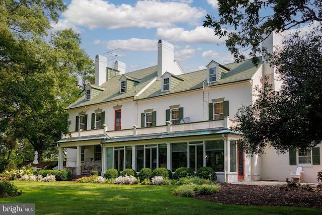 rear view of house featuring a sunroom and a yard