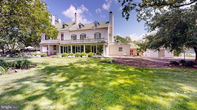 back of property with a lawn and a balcony