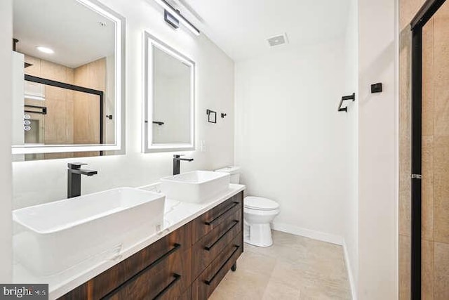 bathroom with vanity, a shower with shower door, and toilet