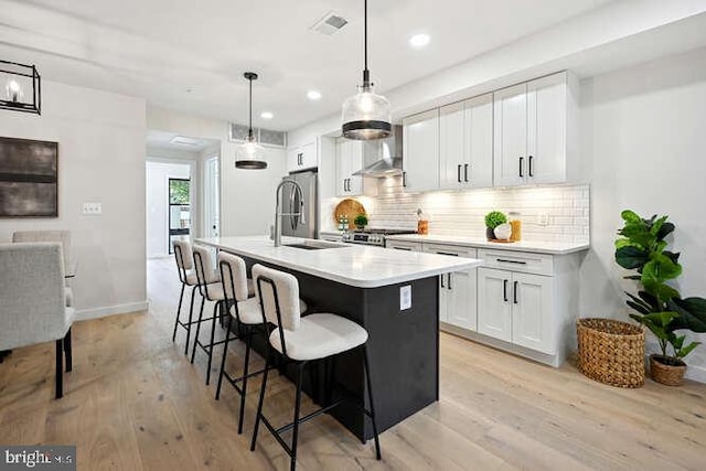 kitchen featuring sink, hanging light fixtures, backsplash, light hardwood / wood-style floors, and white cabinets