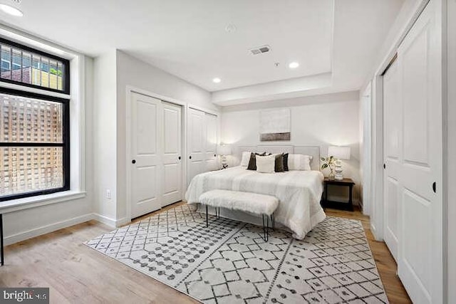 bedroom featuring two closets and light hardwood / wood-style flooring