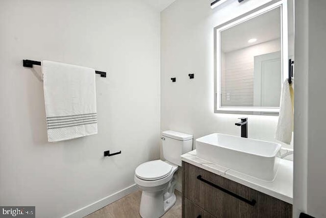 bathroom with wood-type flooring, vanity, and toilet