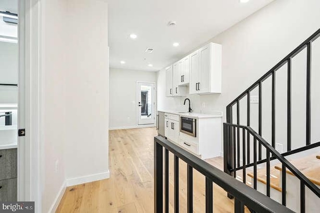 corridor with sink and light hardwood / wood-style floors