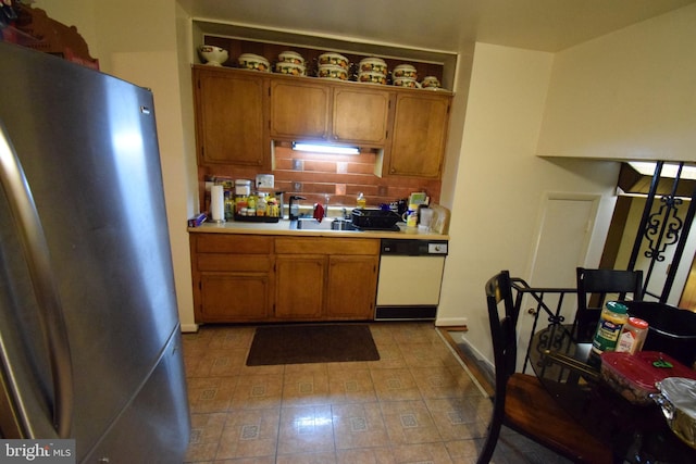 kitchen with stainless steel fridge, backsplash, white dishwasher, and sink