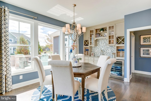 dining space featuring an inviting chandelier, beverage cooler, wood-type flooring, and sink