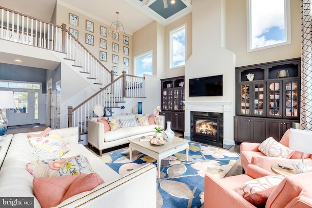 living room with crown molding, a notable chandelier, and a high ceiling