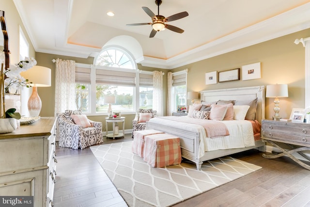 bedroom featuring light wood-type flooring, ceiling fan, crown molding, and a tray ceiling