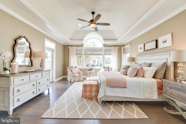 bedroom with ceiling fan, dark hardwood / wood-style flooring, crown molding, and a tray ceiling