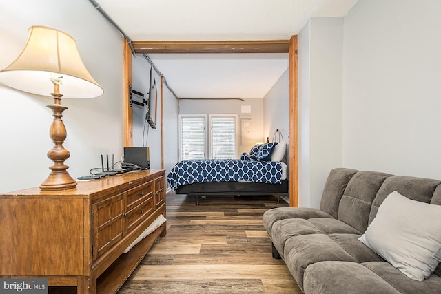 bedroom with hardwood / wood-style floors and beamed ceiling