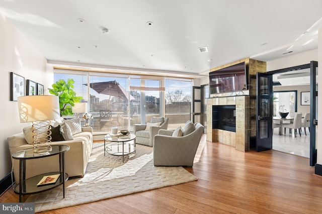 living room with a tiled fireplace and hardwood / wood-style floors