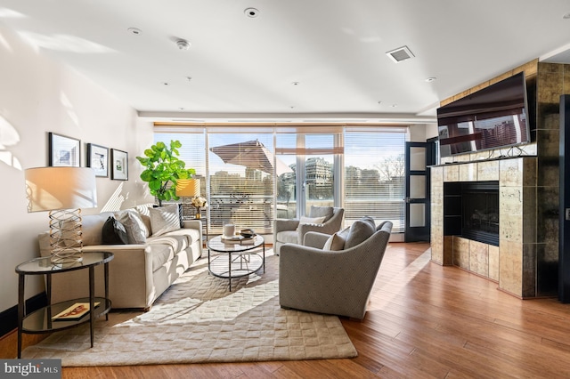 living room featuring a tiled fireplace and hardwood / wood-style flooring