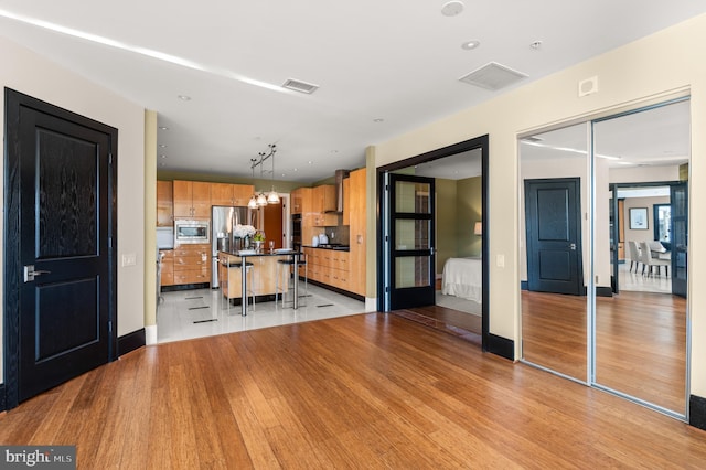 kitchen featuring a breakfast bar, a kitchen island, appliances with stainless steel finishes, decorative light fixtures, and light hardwood / wood-style floors