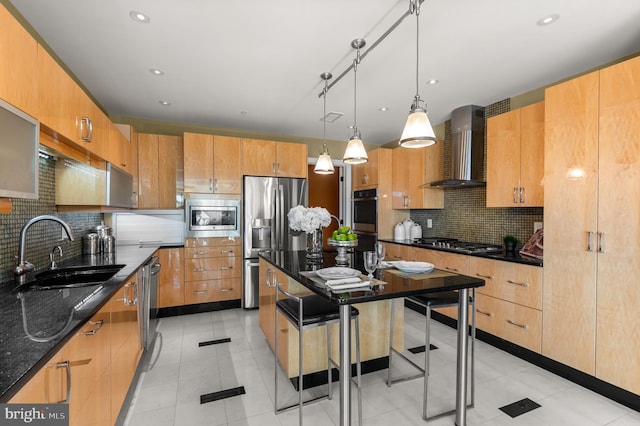 kitchen with sink, a center island, wall chimney range hood, a kitchen breakfast bar, and appliances with stainless steel finishes