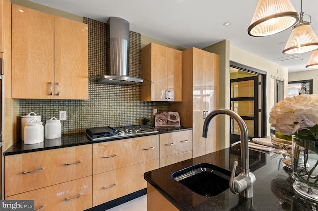 kitchen with wall chimney range hood, sink, hanging light fixtures, tasteful backsplash, and stainless steel gas cooktop