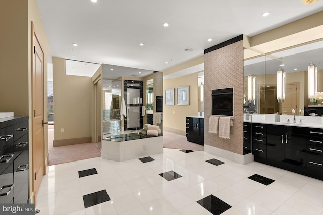 bathroom featuring a large fireplace, tile patterned flooring, vanity, and a bath