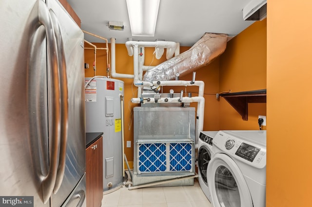 washroom featuring washing machine and clothes dryer, water heater, and light tile patterned floors