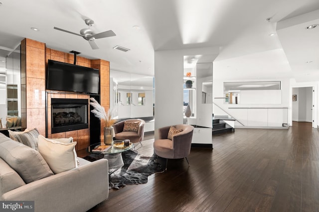 living room with ceiling fan, a fireplace, and dark wood-type flooring