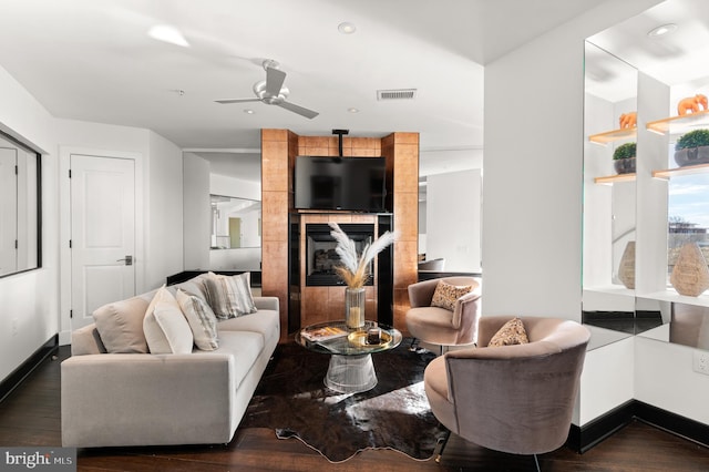 living room with ceiling fan, dark hardwood / wood-style floors, and a tiled fireplace