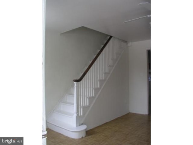 stairway featuring parquet flooring