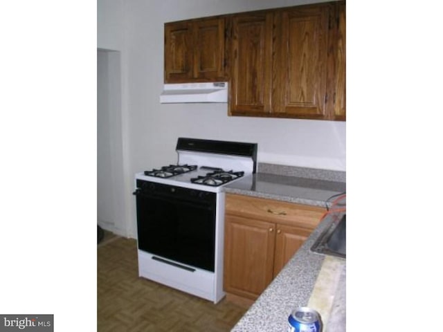 kitchen featuring white gas stove and parquet flooring