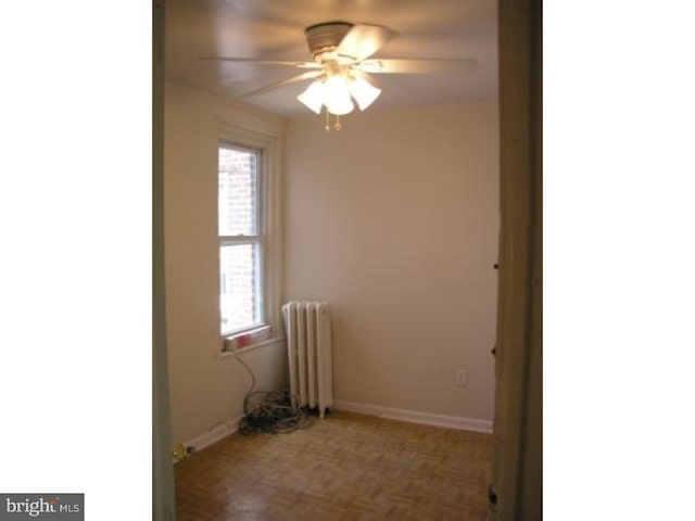 spare room featuring ceiling fan, radiator heating unit, and parquet flooring