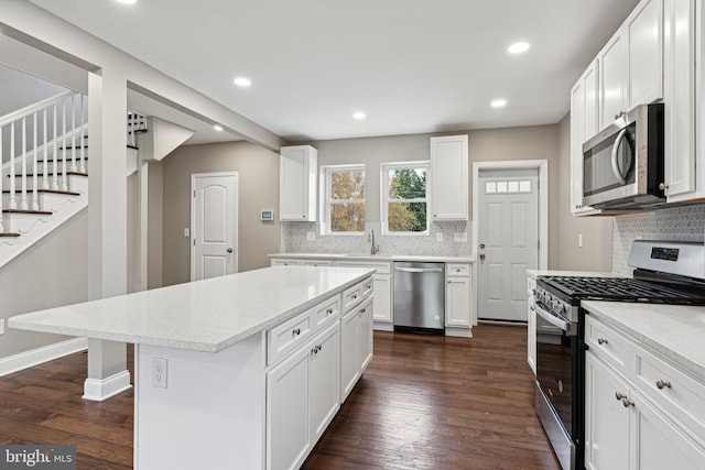 kitchen with stainless steel appliances, a kitchen island, and white cabinetry