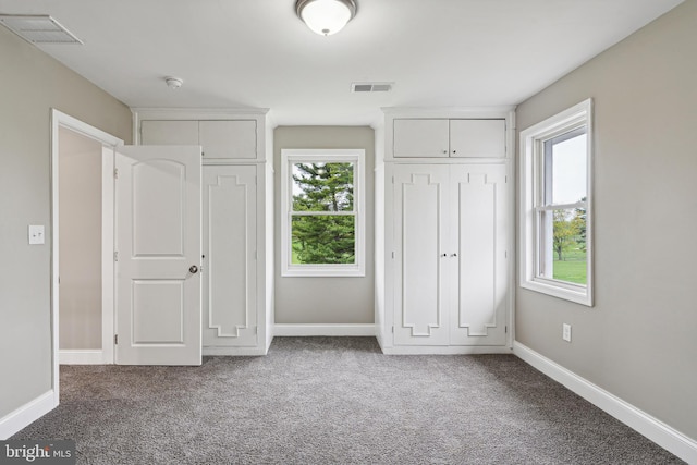 unfurnished bedroom featuring carpet flooring and multiple windows