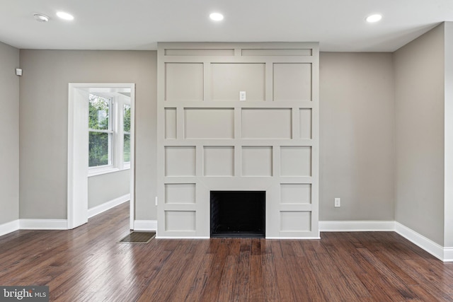 unfurnished living room featuring built in features and dark wood-type flooring