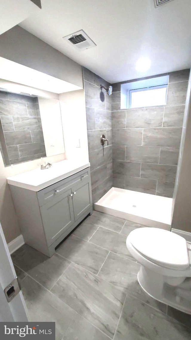 bathroom with vanity, toilet, and tiled shower