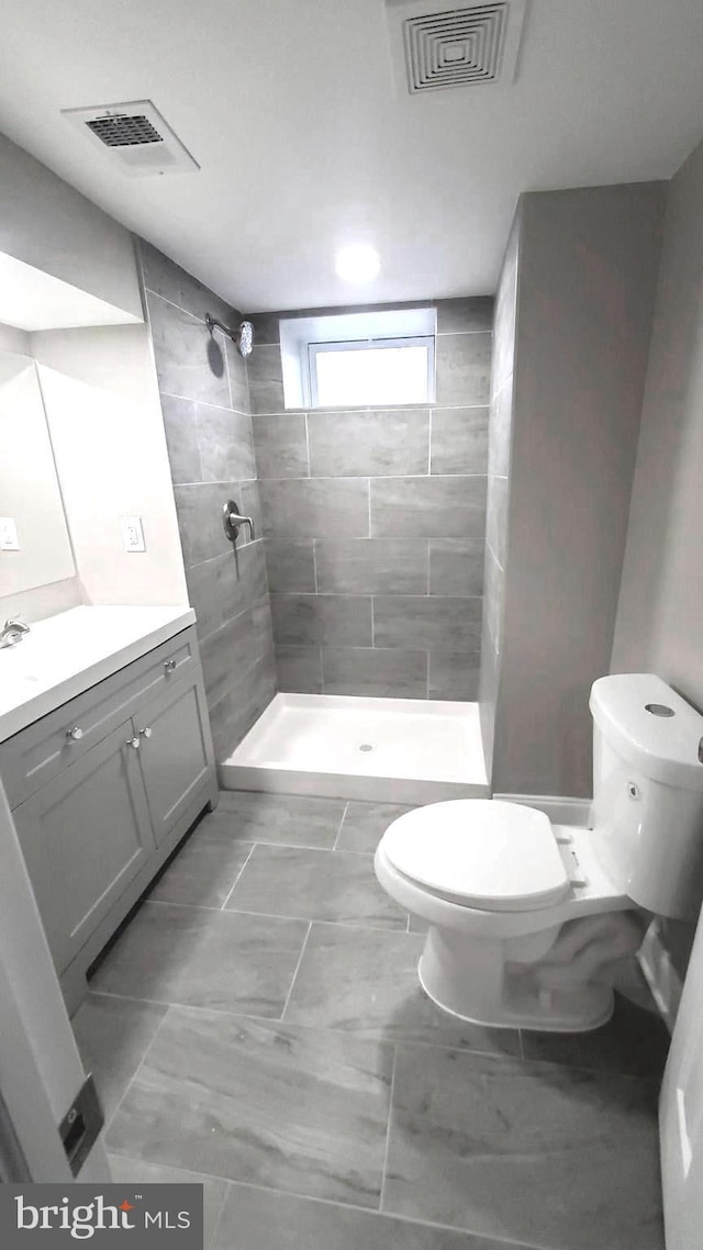 bathroom featuring tiled shower, vanity, and toilet