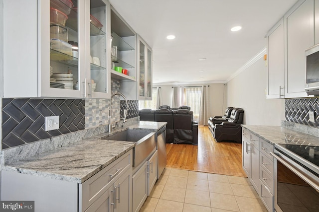 kitchen with sink, stainless steel dishwasher, light stone countertops, light tile patterned floors, and ornamental molding