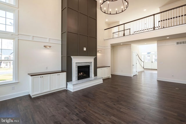 unfurnished living room featuring a notable chandelier, dark wood-type flooring, and a high ceiling