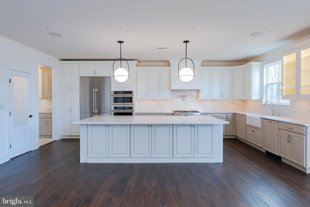 kitchen featuring white cabinetry, sink, a center island, hanging light fixtures, and appliances with stainless steel finishes