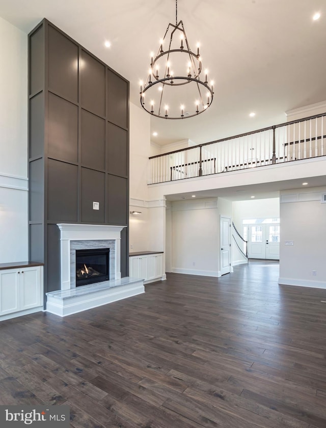 unfurnished living room with a towering ceiling, dark hardwood / wood-style floors, and a notable chandelier