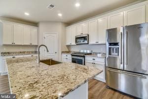 kitchen featuring white cabinets, sink, a kitchen island with sink, and appliances with stainless steel finishes