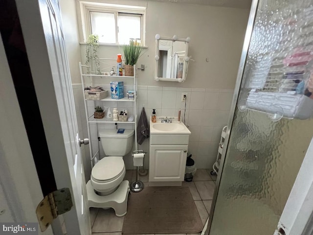 bathroom with tile patterned floors, an enclosed shower, vanity, tile walls, and toilet