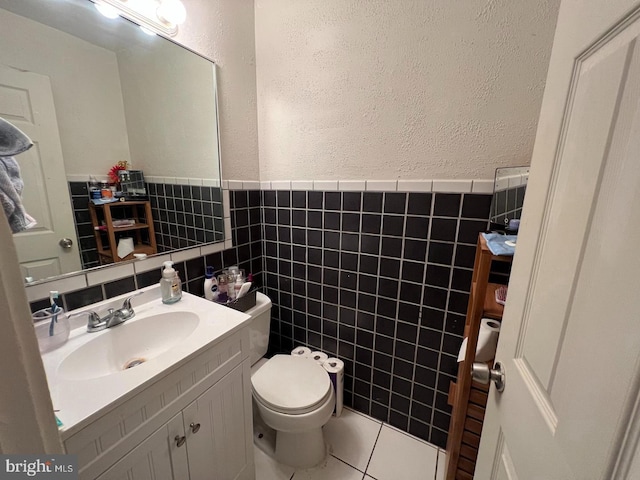 bathroom featuring tile patterned flooring, vanity, toilet, and tile walls