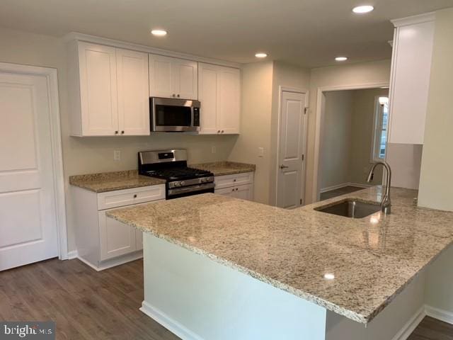 kitchen with kitchen peninsula, white cabinetry, sink, and stainless steel appliances